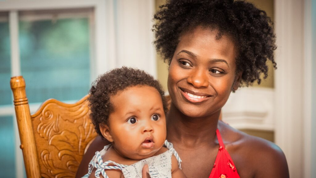 woman in orange shirt carrying baby in white top: myths about life after pregnancy