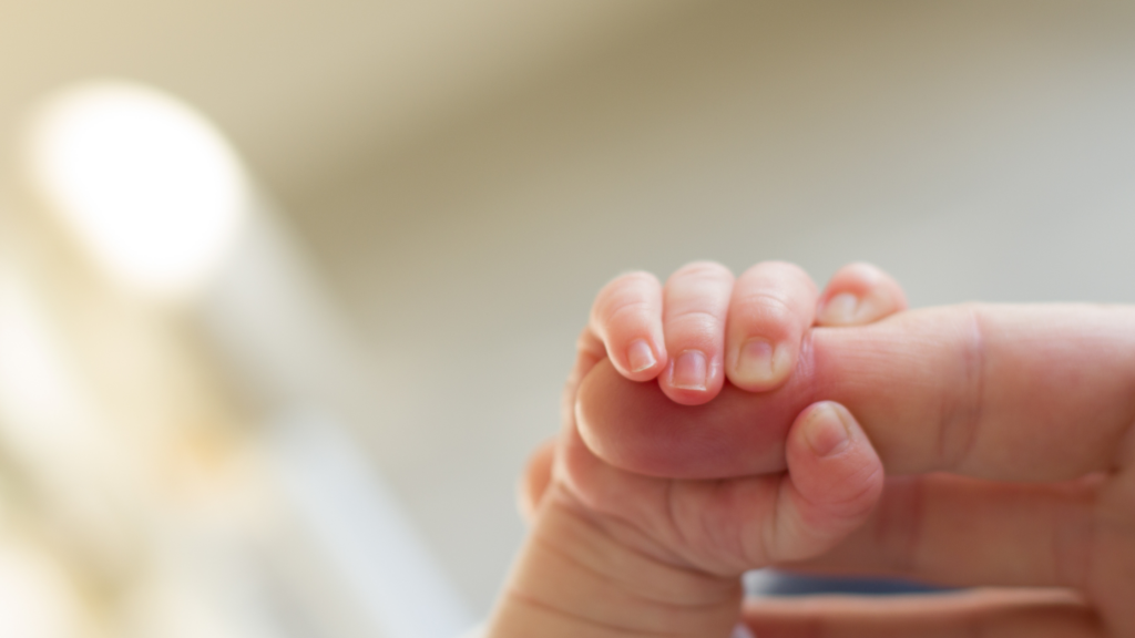 Baby hand holding adult finger